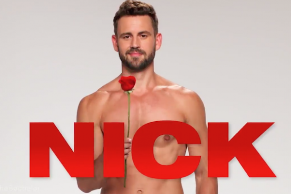Nick is standing shirtless, holding a rose. His name is written in giant red letters in front of him.