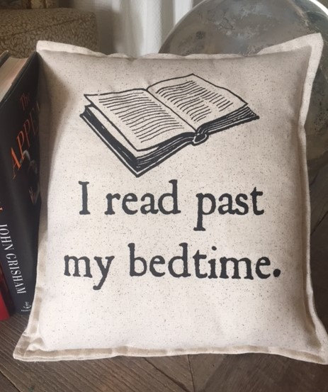 A pillow with a book picture that says I read past my bedtime 