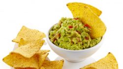 A bowl of guacamole with tortilla chips.