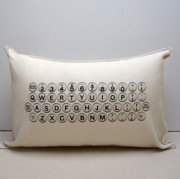 A white fabric pillow with typewriter keys screen printed on the front