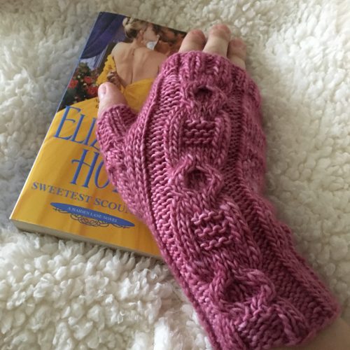 A pair of knitted wrist warmers in a dark pink
