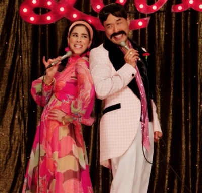 Sarah Silverman and Randall Park dressed like Sonny and Cher, with those weird, long thin microphones