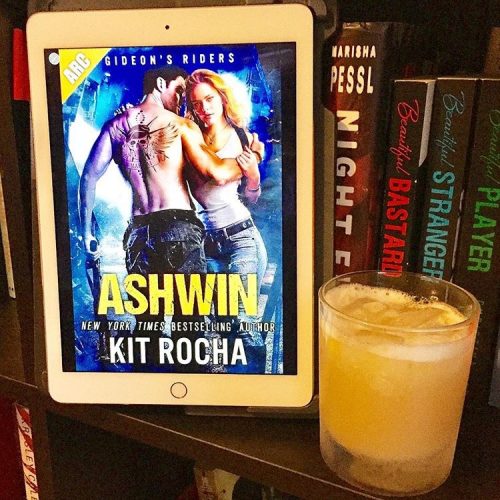 A copy of Ashwin on a bookshelf next to a whiskey sour.