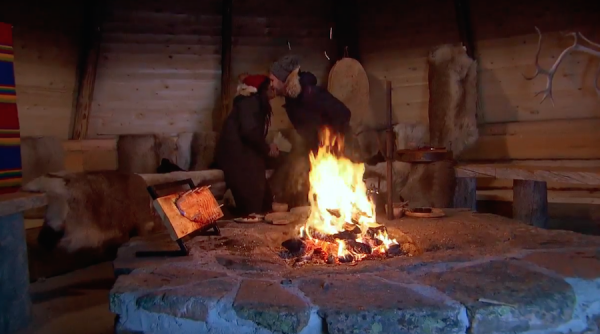 Nick and Rachel kiss in front of a fire