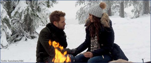 Nick and Vanessa sit outside next to a fire.