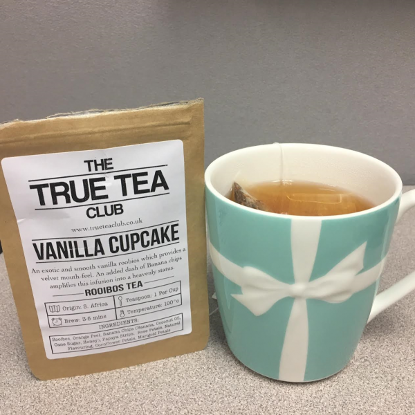 The package of Vanilla Cupcake Roobios sits next to a blue Tiffany teacup filled with tea. Update: my desk is still the color of depression.