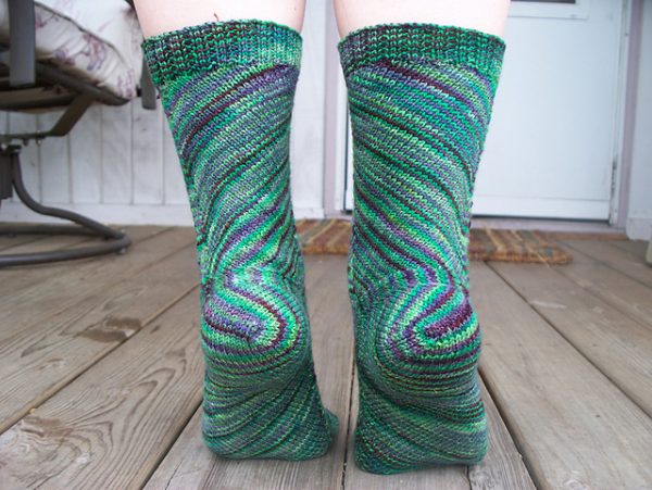 A close up on a pair of green and purple socks with a swirling pattern. 