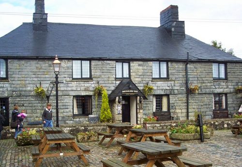 The Inn from the outside - a low stone building with a courtyard with picnic tables 