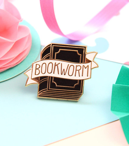 Black and white enamel Bookworm pin with a white ribbon wound around a book