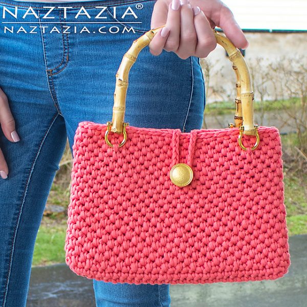 A rectangular shaped purse with a bamboo handle and button enclosure.