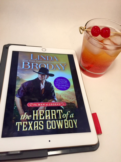 A copy of The Heart of a Texas Cowboy next to a cocktail