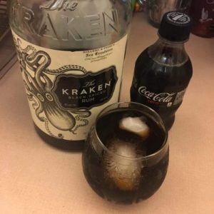 A giant bottle of Kraken rum, a small bottle of Coke Zero, and my drink sit on my kitchen counter.