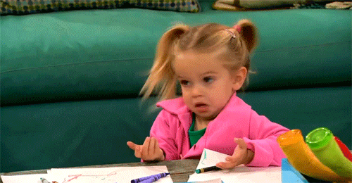 A little girl shakes her head and holds up her hands like IDK