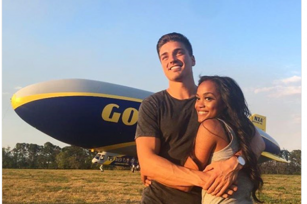 Dean and Rachel hug in front of the Goodyear blimp