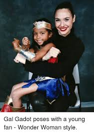 Gal Godot posing with a young girl in a wonder woman costume, arms crossed