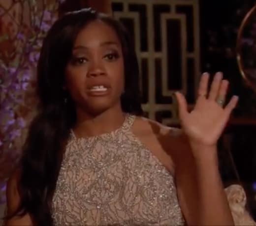 Rachel has her hand thrown up in frustration, her eyes teary.