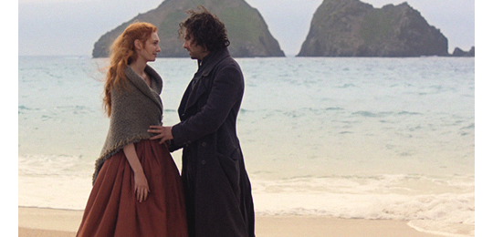 Ross and D on the beach. Ross is touching her belly.
