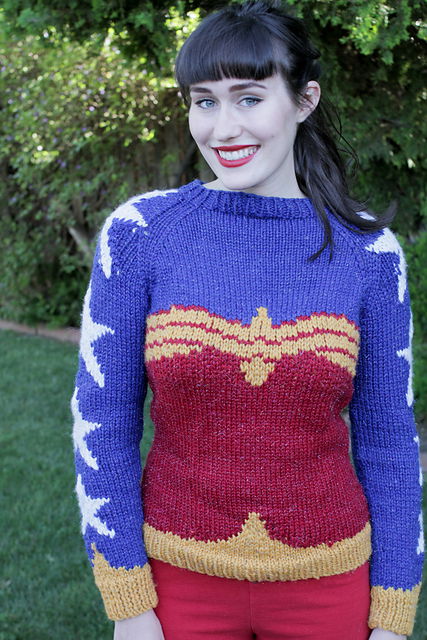 A woman models a pullover sweater designed to look like Wonder Woman's bodice against a blue backdrop with stars.