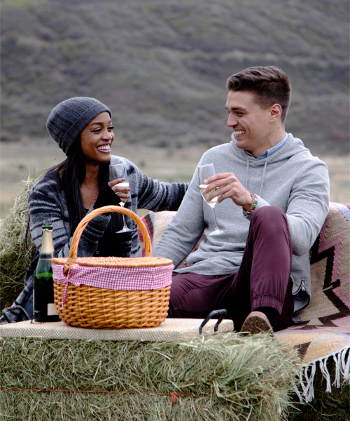 Dean and Rachel sit on hay bales and enjoy a picnic.