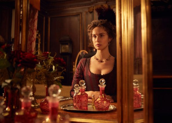 Elizabeth, in her red striped gown, gazing at herself in her mirror, considering her life and her choices.