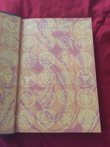 The end papers of The Library of Light and Shadow. They're a deep yellow with what looks to be alchemical symbols.