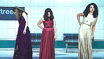 Sutton, Jane, and Kat, in fancy evening gowns, twitching thier skirts and looking kind of uncomfortable, in a subway platform