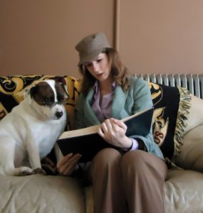 JA Author Photo - She's sitting on a couch, reading to her cute dog.