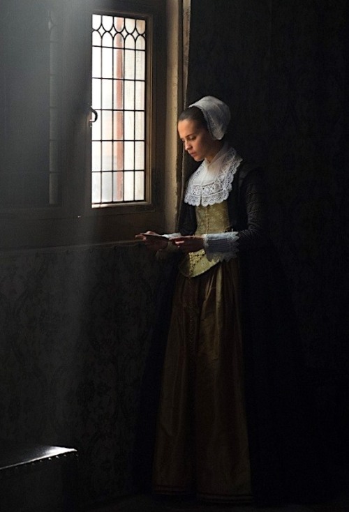 Alicia Vikander, next to a window with a letter. The shot is composed like a Vermeer painting with light streaming in.