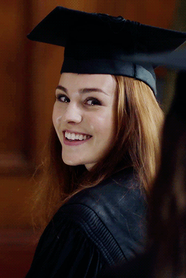 Brianna, a high school graduate in her cap and gown, grinning back at her parents.