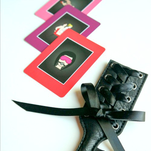 Close up of items featured in the Hurts So Good Bawdy Bookworm box, including a leather paddle.