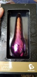 The Unihorn vibe, a twisty unicorn horn vibrator with 10 speed settings in a shiny color that changes from gold at the top to pink at the bottom