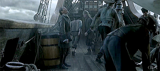 Yi Tien Cho standing in the rain on deck as the sailors bustle around him.