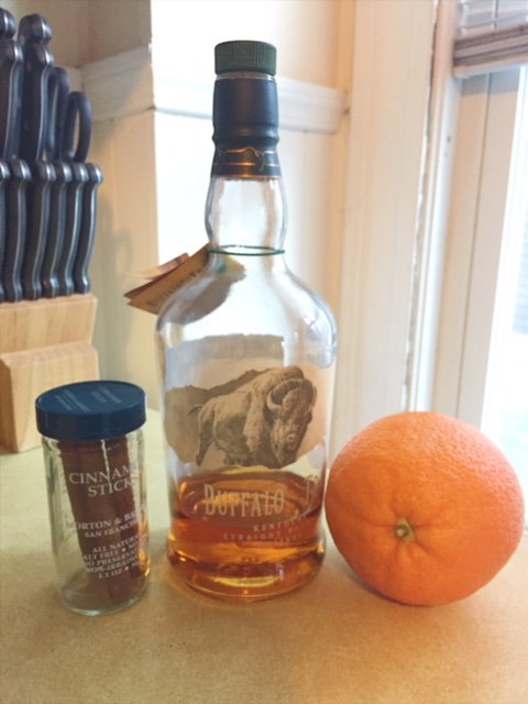 Ingredients for the Forbidden Fruit cocktail cinnamon stick bourbon and an orange