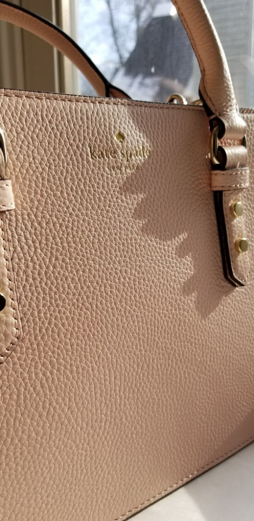pink pebbled leather exterior of bag with kate spade logo