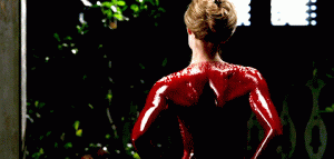 Geillis, covered in blood from the neck down, facing away from the camera.