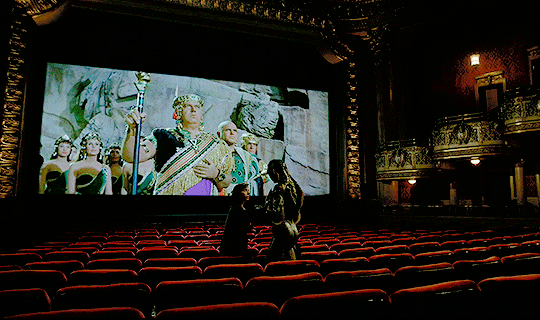 Elisa and Amphibian Man, standing in the seats of the movie palace, while The Story of Ruth plays on the screen. The butt is perfect.