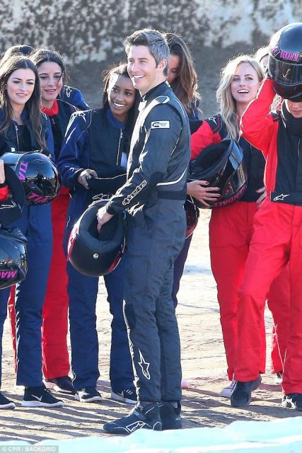 Arie and the girls stand around in racing gear.