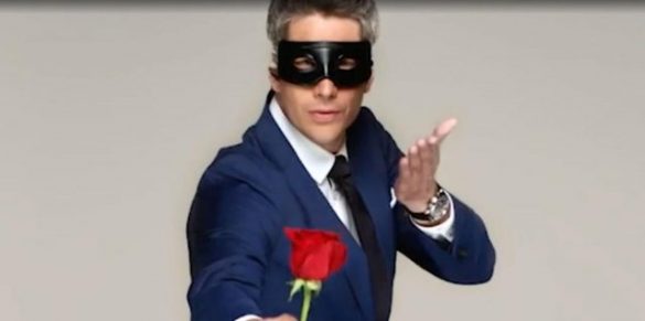 Arie is wearing a black mask, holding a rose, and blowing a kiss.