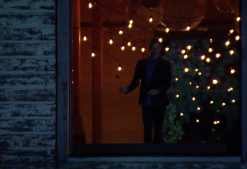 Arie looking forlorn as he holds a rose and looks out a window