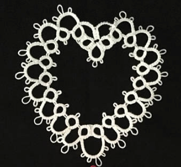 A white tatted lace heart against a black background