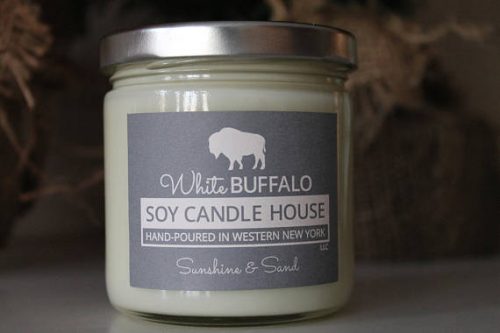 A soy candle with a grey label with a white buffalo stamped on it