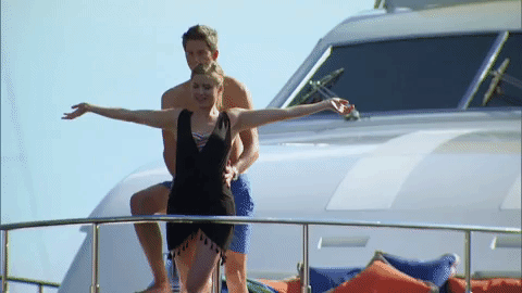 Chelsea and Arie stand on the bow of the yacht