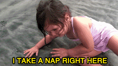 A little girl lies down in the sand and says I take a nap right here.