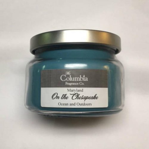 A dark blue green candle in a glass jar.