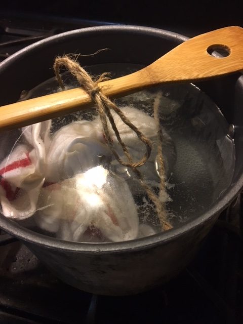 The pudding in the water, suspended from a wooden spoon.