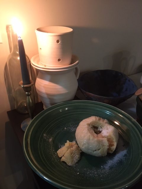  sussex pond pudding which sort of looks like a donut on a stonewear plate with a ceramic pot and lid in the background