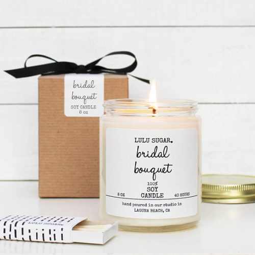 Lulu Sugar Bridal Bouquet candle. A white candle next to a small cardboard box wrapped with a black bow