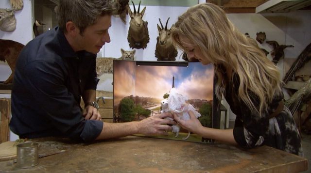 Kendall and Arie hold taxidermy rats, dressed as a bride and a groom, in front of a diorama of Paris