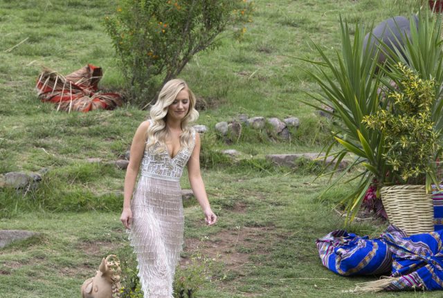 Lauren walks through a field. She's wearing a silvery white fringed dress.