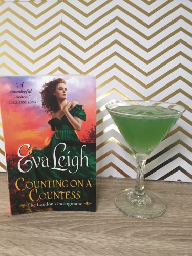 Counting on a Countess next to a green drink in a martini glass. It's shot in front of a gold chevron background.